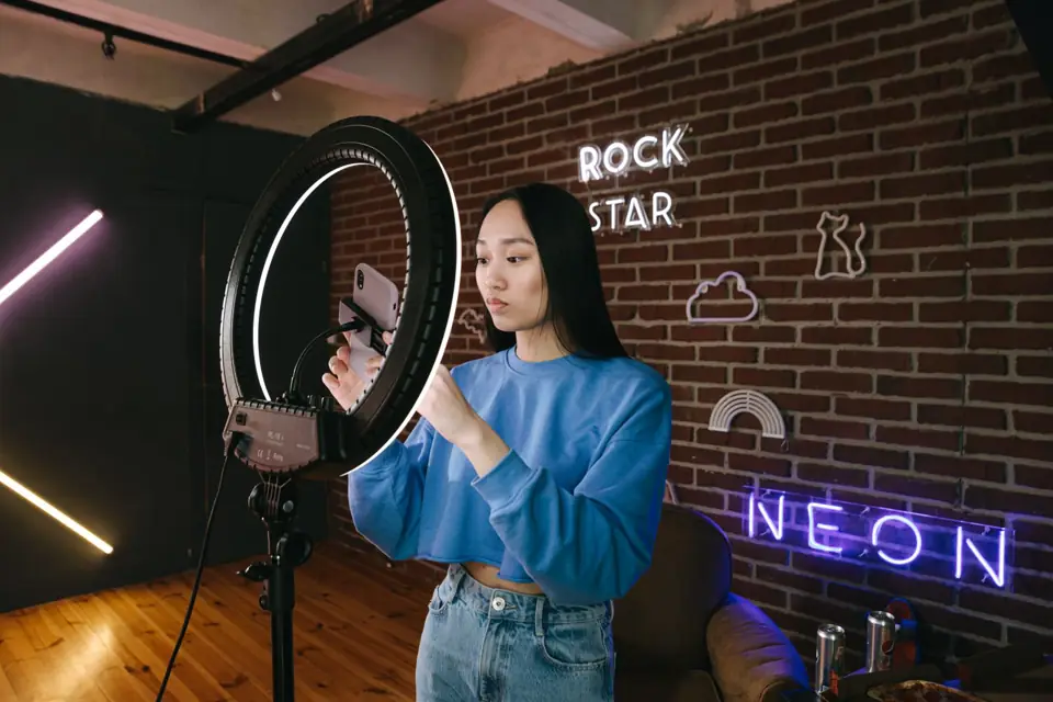 Người làm nội dung chỉnh điện thoại trên giá đèn vòng, chuẩn bị quay video giới thiệu sản phẩm